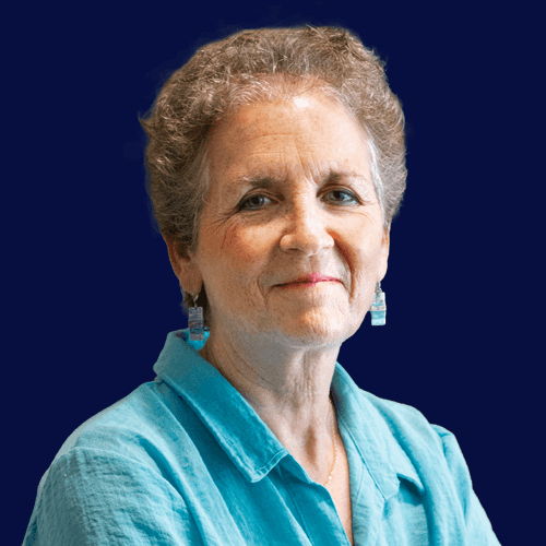 Headshot of woman with short, curly, light brown hair and fair skin. She wears a light blue collared shirt, against a navy background.